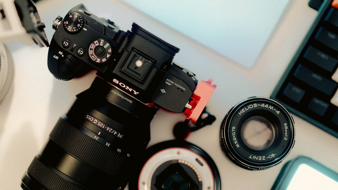 About A top view of a camera and lenses on a desk, showcasing photography equipment.